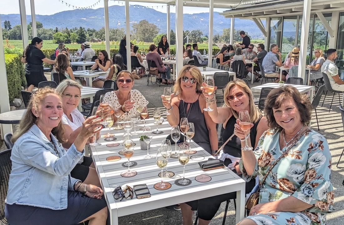 Wine tour guests raising glasses of wine at a table on a sunny winery patio in Edna Valley