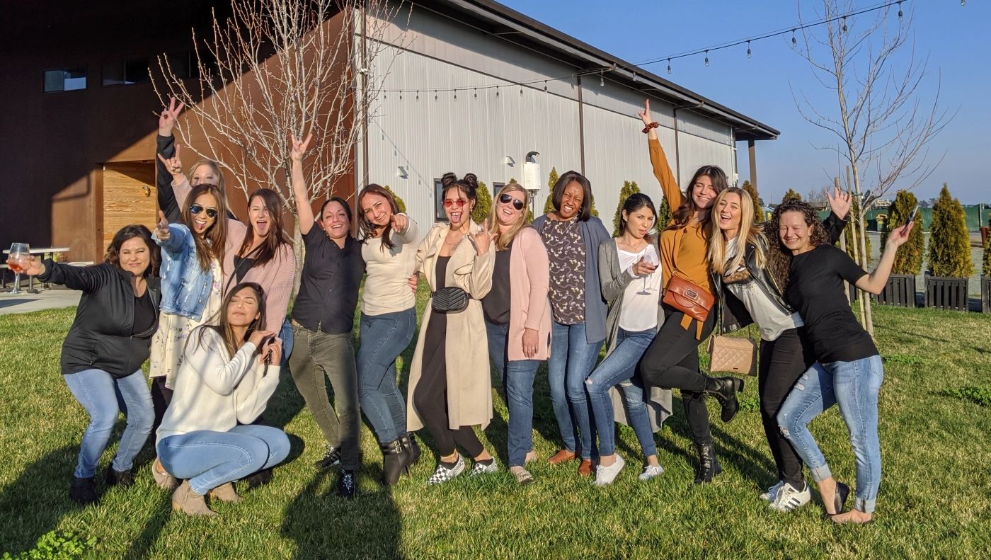 Group of guests cheering with wine glasses on the lawn at a Temecula winery during a designated driver wine tour